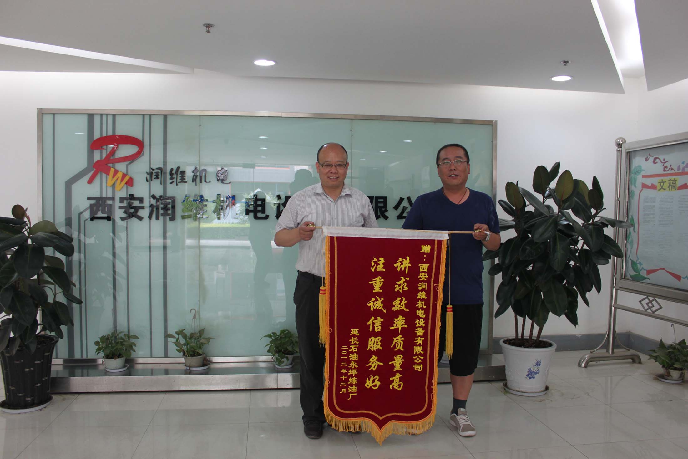 董事长王立友先生与永坪炼油厂陈科长持锦旗合影(1)